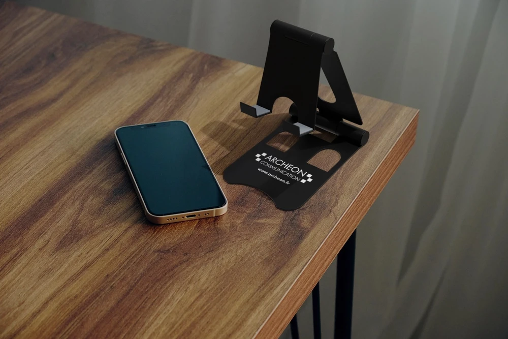 Photographie professionnelle en plan moyen montrant un détail de technique de broderie en cours ou finalisée : aiguille, fil de broderie coloré (rouge, bleu, or) sur tissu tendu dans un cercle à broder, mettant en avant les points de broderie nets et réguliers, la texture du fil et la précision du travail artisanal. Lumière douce et focalisée, fond légèrement flou, surface de travail légèrement visible pour contextualiser le savoir-faire technique d'Archéon.